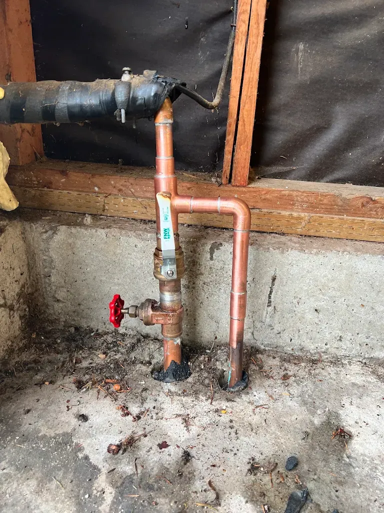 Copper water main entering a crawlspace with ball valve and hose bib drain