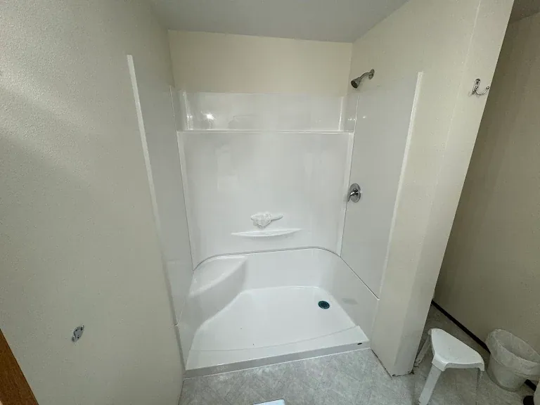 White fiberglass shower stall installed with new valve and shower head