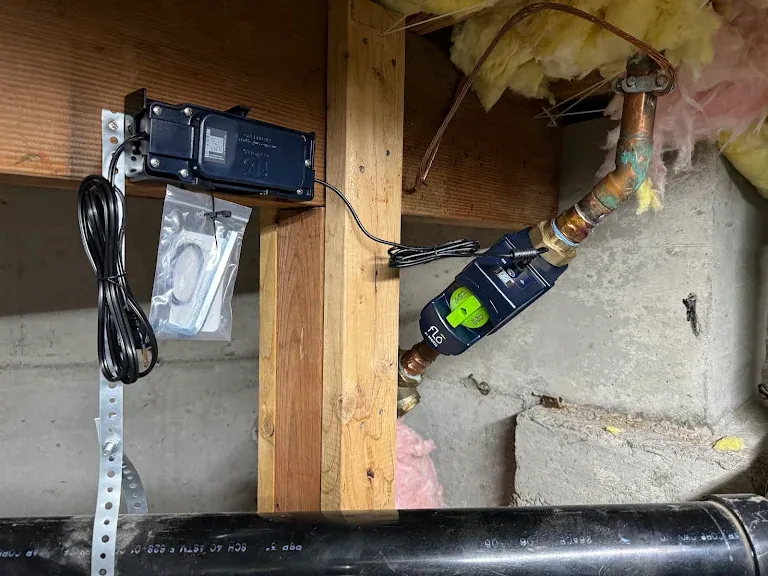 Flo by Moen smart water shutoff valve installed on a copper main in a crawlspace with its controller mounted to a joist
