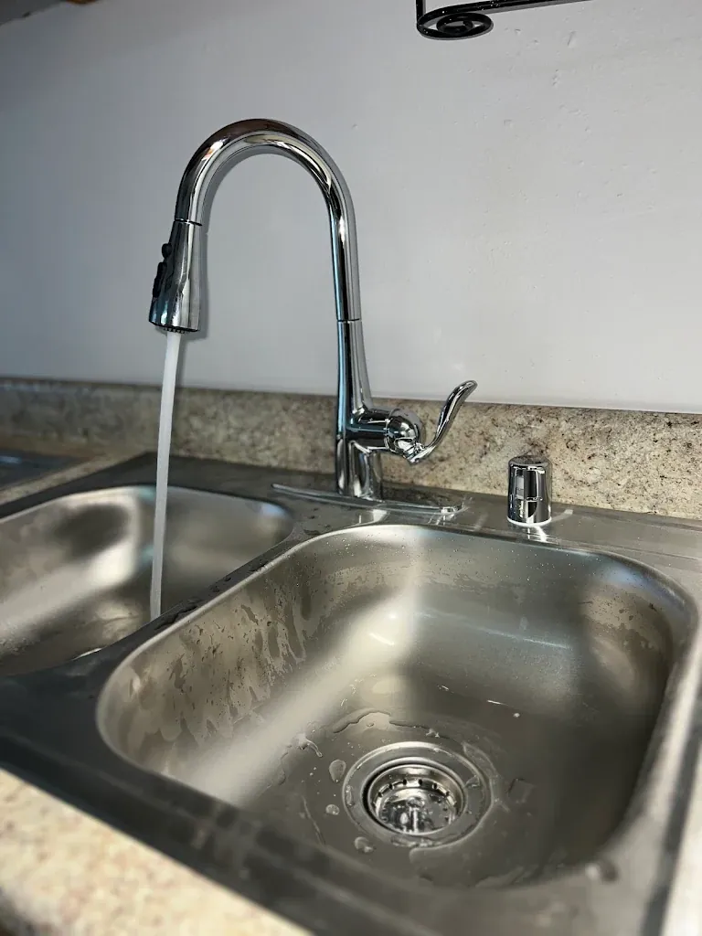 Chrome pulldown kitchen faucet running into a stainless sink