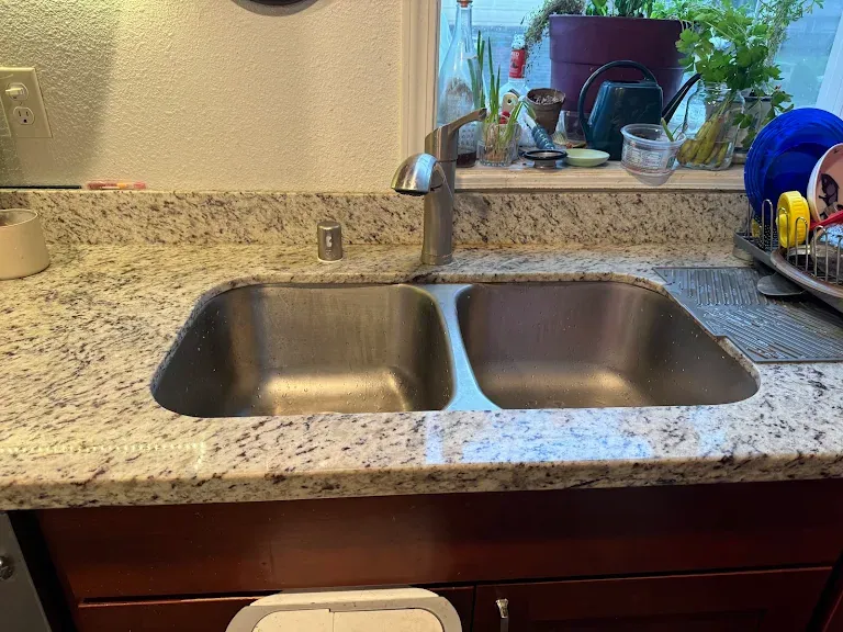 Double-bowl undermount stainless sink with new faucet in a granite countertop