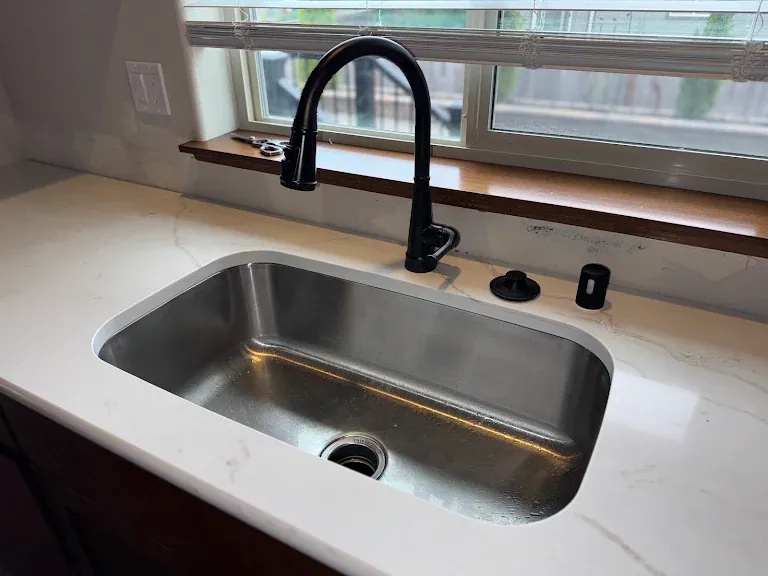 Undermount stainless sink with matte black pulldown faucet in a white quartz countertop