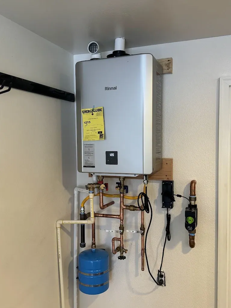 Rinnai tankless water heater mounted on a wall with copper piping, isolation valves, expansion tank and Flo smart valve