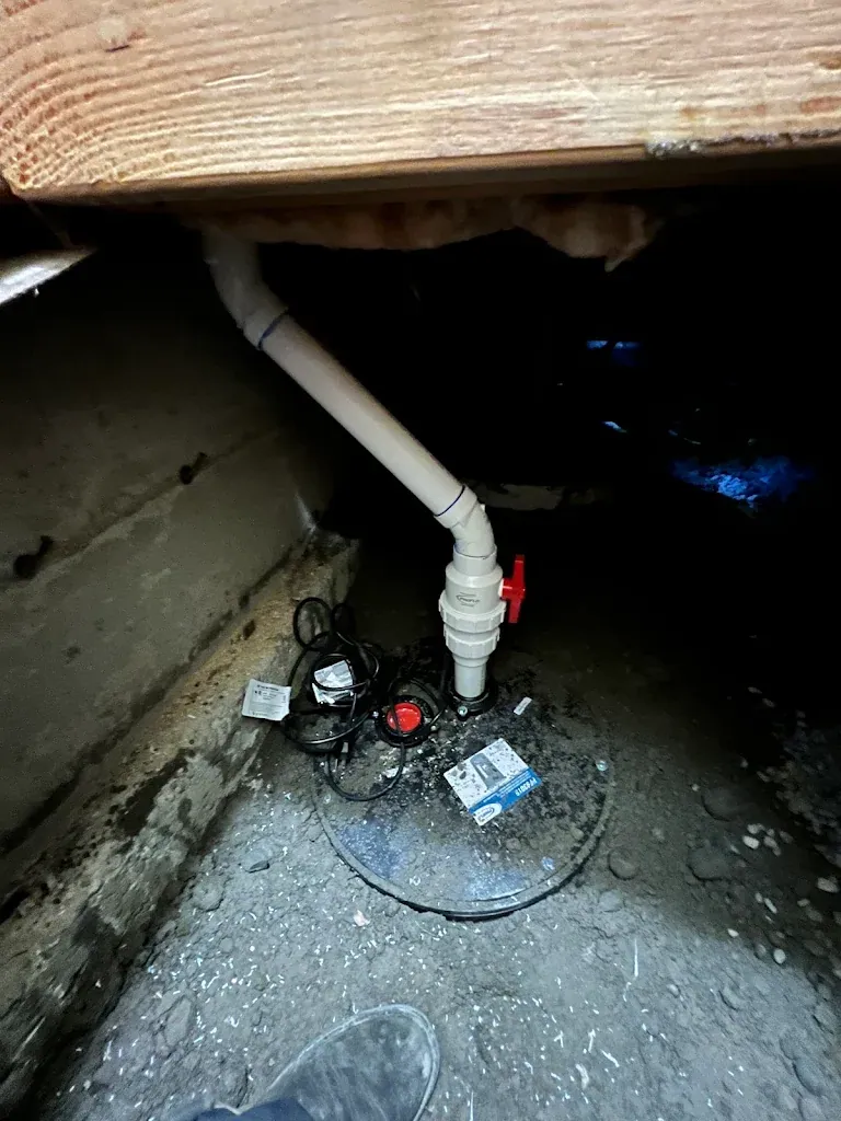 Sealed sump basin lid with discharge pipe and valve installed in a crawlspace