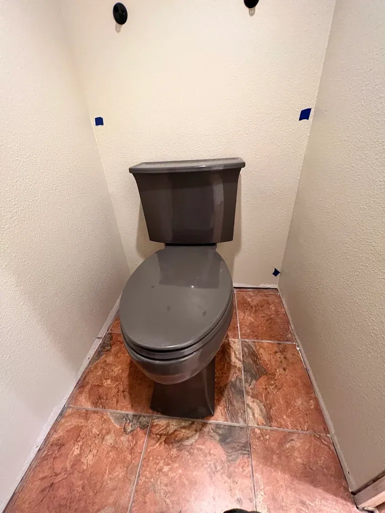 Gray elongated toilet installed in a small bathroom with tile floor